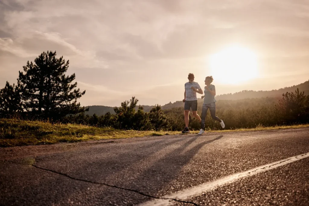 Couple running along a countryside road at sunset