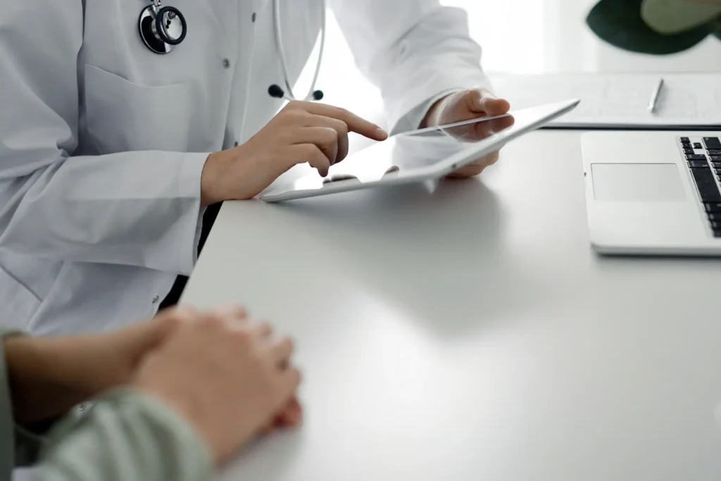 Doctor consulting with a patient and writing notes on a clipboard.