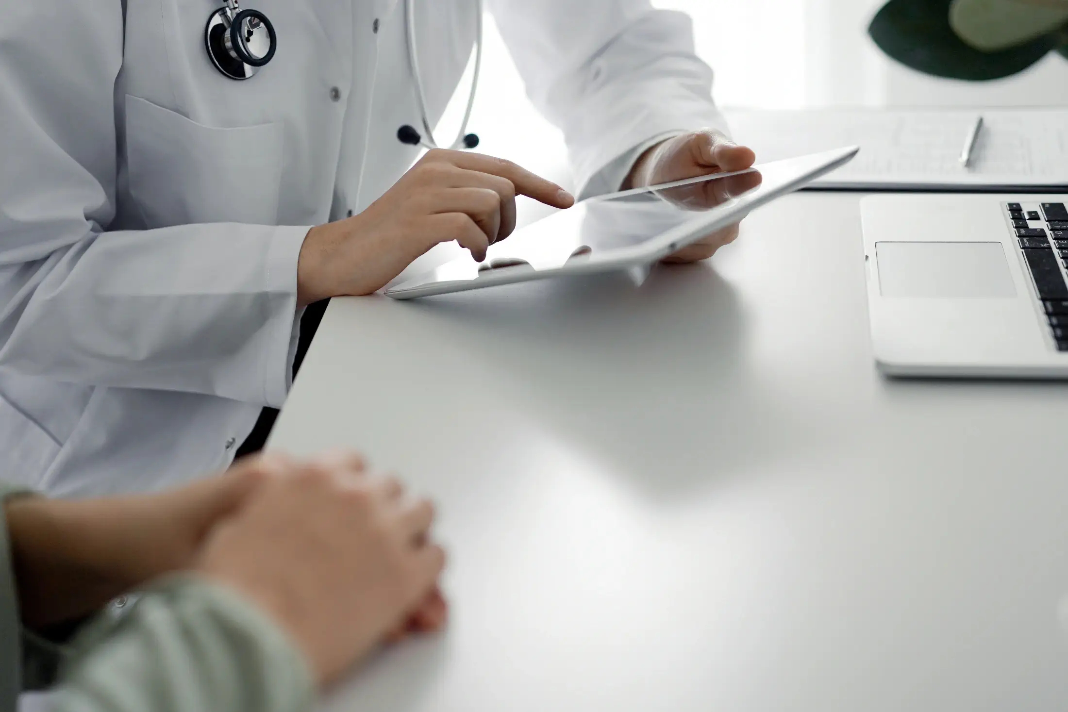 Doctor consulting with a patient and writing notes on a clipboard.